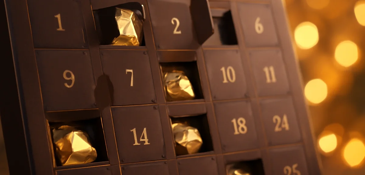 A close-up of an elegant chocolate advent calendar opened to reveal small individually wrapped choco
